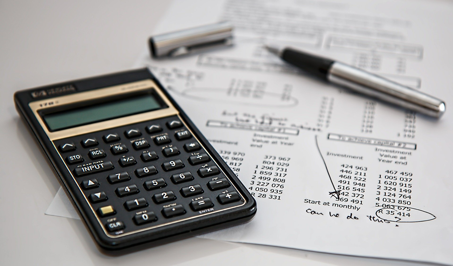 calculatrice sur feuille de factures avec chiffres entoures par un crayon