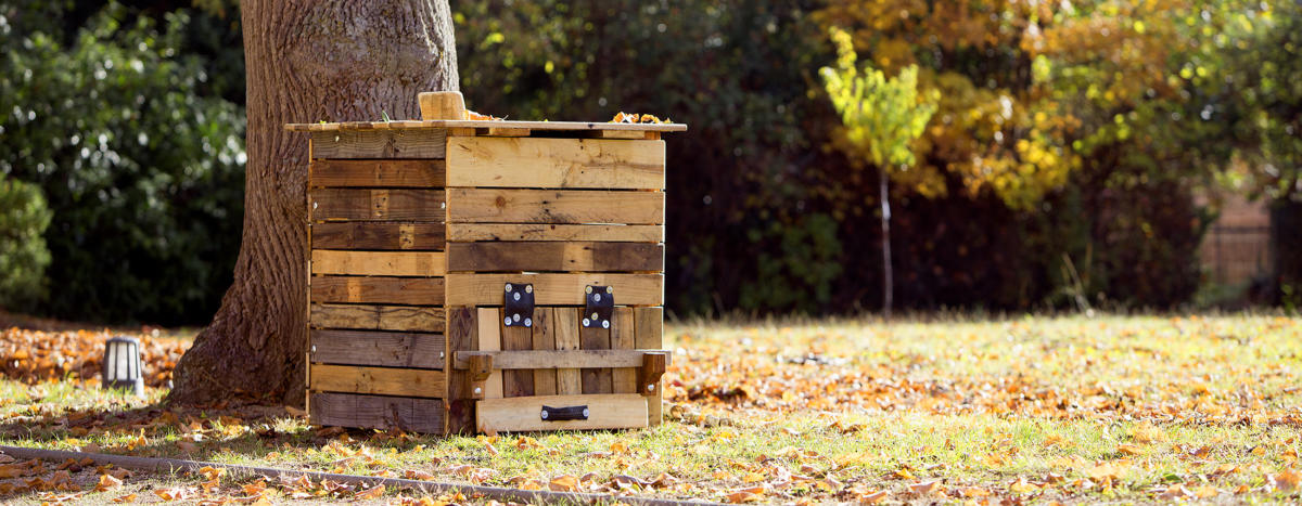 composteur en bois au pied d'un arbre dans un jardin